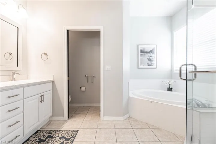 Bathroom with toilet, vanity, tiled bath, and tile patterned floors