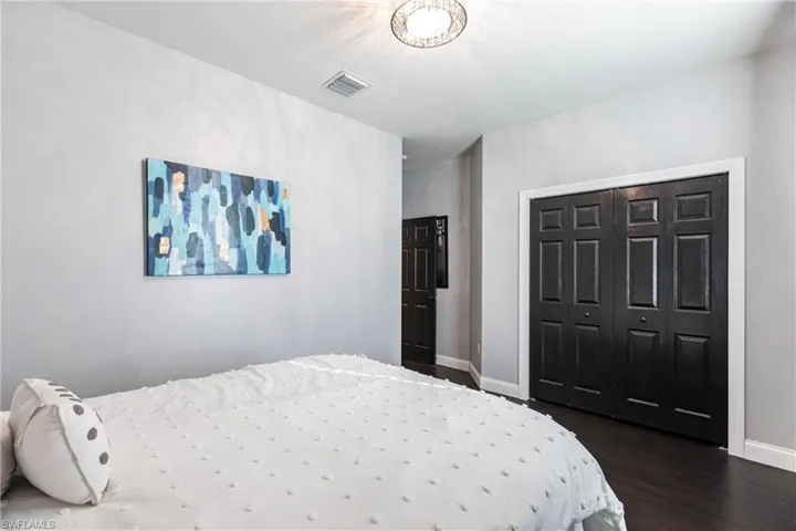 Bedroom with dark hardwood / wood-style flooring and a closet
