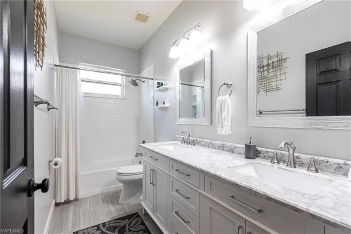 Full bathroom featuring tile patterned flooring, vanity, toilet, and shower / bathtub combination with curtain