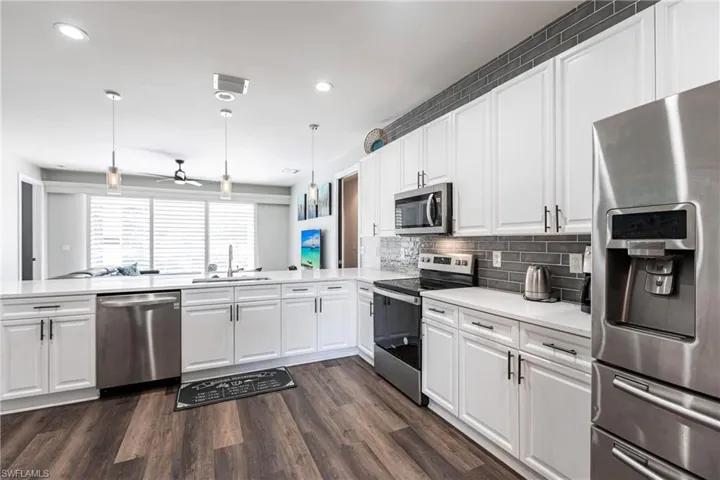 Kitchen with decorative light fixtures, kitchen peninsula, sink, and appliances with stainless steel finishes