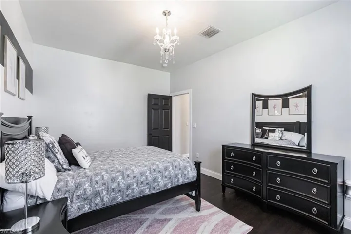 Bedroom with an inviting chandelier and dark wood-type flooring