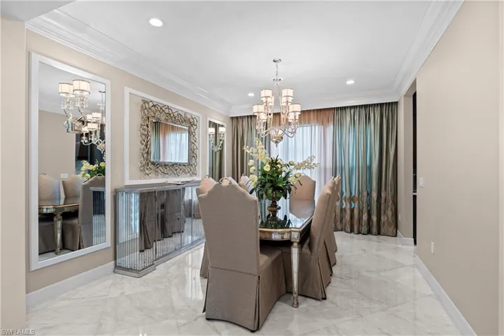 Spacious room featuring high ceilings, a grand chandelier, large windows with full-length drapes, recessed lighting, and large format polished tile flooring