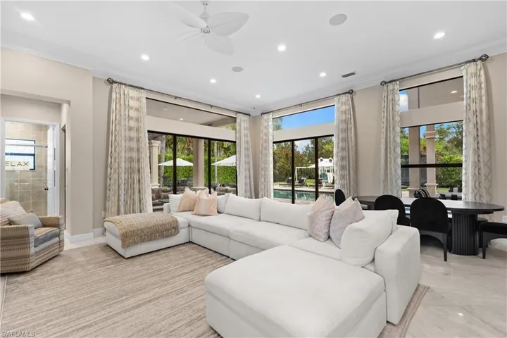 Spacious living area featuring large format tile flooring and an expansive window wall with exterior pool access