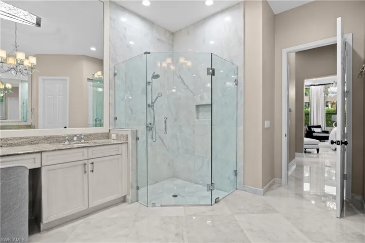 Spacious bathroom featuring a glass-enclosed walk-in shower with tile surround, a built-in shower niche, and a handheld showerhead
