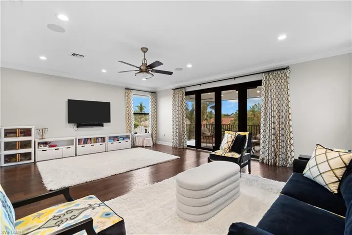 Spacious living area featuring dark wood-finish flooring, recessed lighting, and a ceiling fan