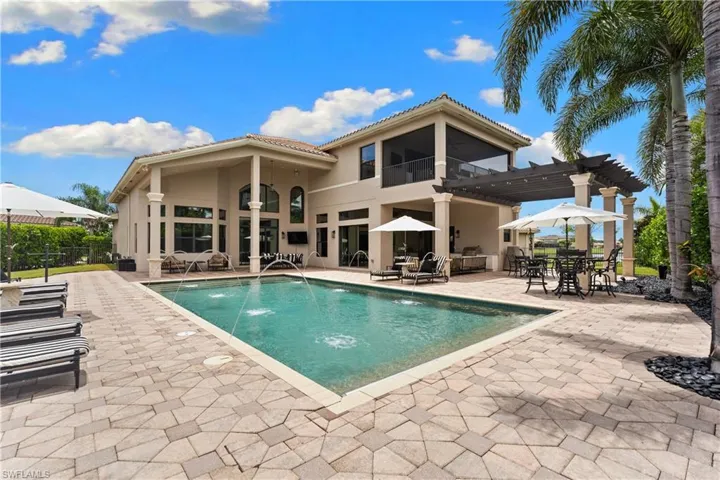 Expansive paver patio surrounding a rectangular swimming pool with water features