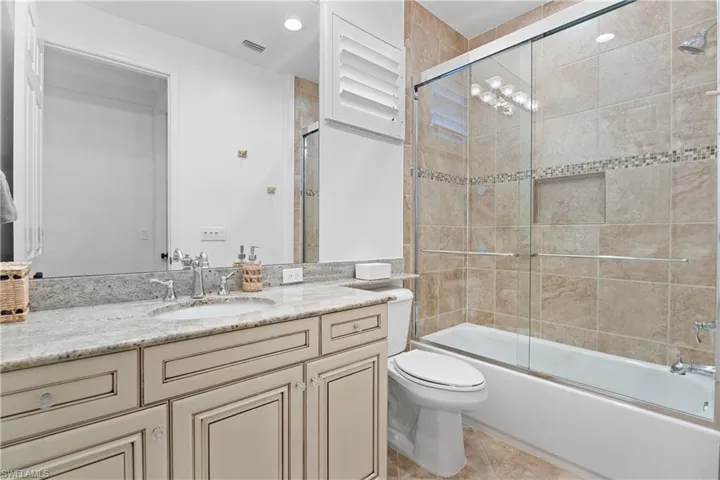 Bathroom featuring a single vanity with stone countertop, undermount sink, and chrome fixtures