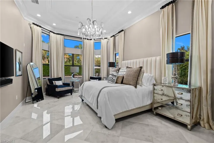Spacious room featuring high ceilings, a grand chandelier, large windows with full-length drapes, recessed lighting, and large format polished tile flooring