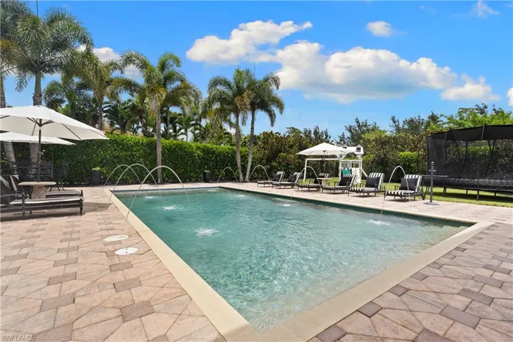 Rectangular swimming pool featuring multiple water fountains and a light-colored coping