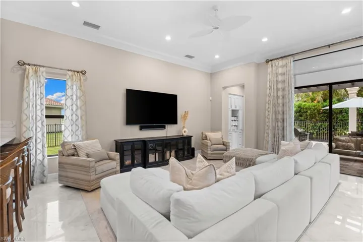 Spacious living area featuring polished tile flooring, recessed lighting, and crown molding