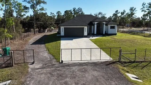 French country inspired facade with a fenced front yard, a gate, driveway, a garage, and stucco siding