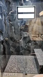 Full bath featuring a marble finish shower and plenty of natural light