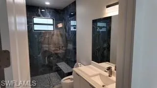 Full bathroom featuring vanity and a marble finish shower