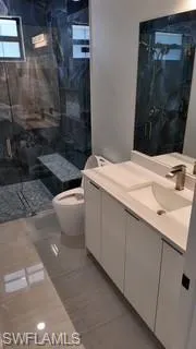 Full bath featuring vanity and a marble finish shower