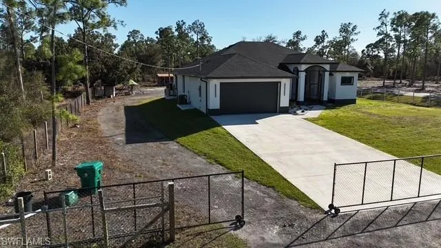 View of front of property with a fenced front yard, driveway, stucco siding, a garage, and a gate