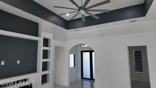 Unfurnished living room with arched walkways and ceiling fan