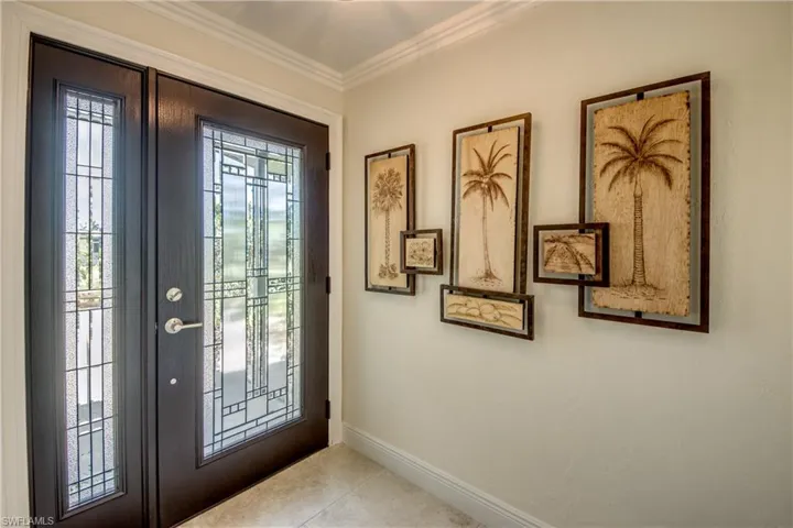 Tiled foyer entrance featuring ornamental molding and a wealth of natural light