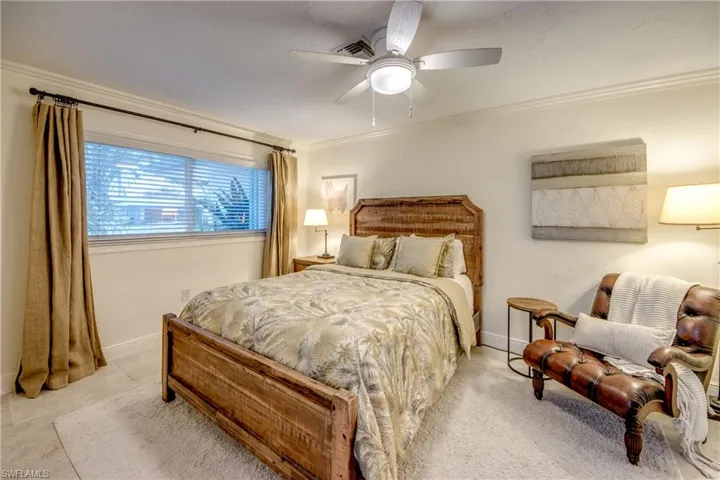 Tiled bedroom featuring ceiling fan and ornamental molding