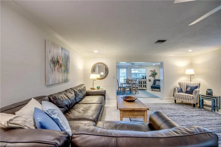 Carpeted living room featuring ornamental molding and ceiling fan