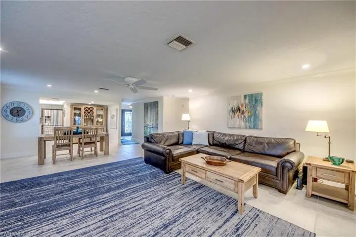 Living room with crown molding, ceiling fan, and light tile patterned floors