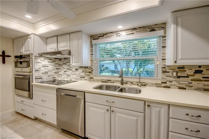 Kitchen featuring ceiling fan, stainless steel appliances, white cabinets, sink, and backsplash