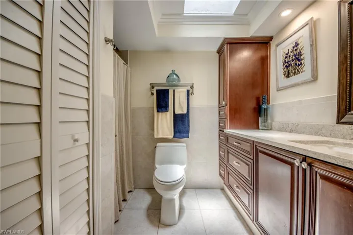 Bathroom featuring vanity, tile patterned floors, tile walls, a tray ceiling, and toilet