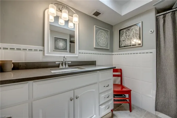 Bathroom with tile walls, tile patterned floors, and vanity
