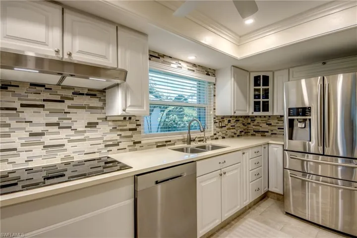 Kitchen featuring sink, tasteful backsplash, white cabinets, and stainless steel appliances