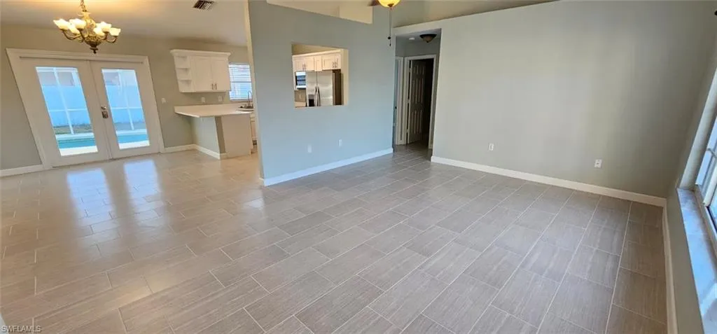 Unfurnished living room with hanging lights and french doors