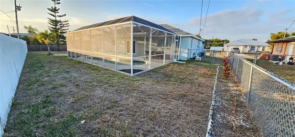 Back of house featuring a sunroom, a fenced backyard, and glass enclosure