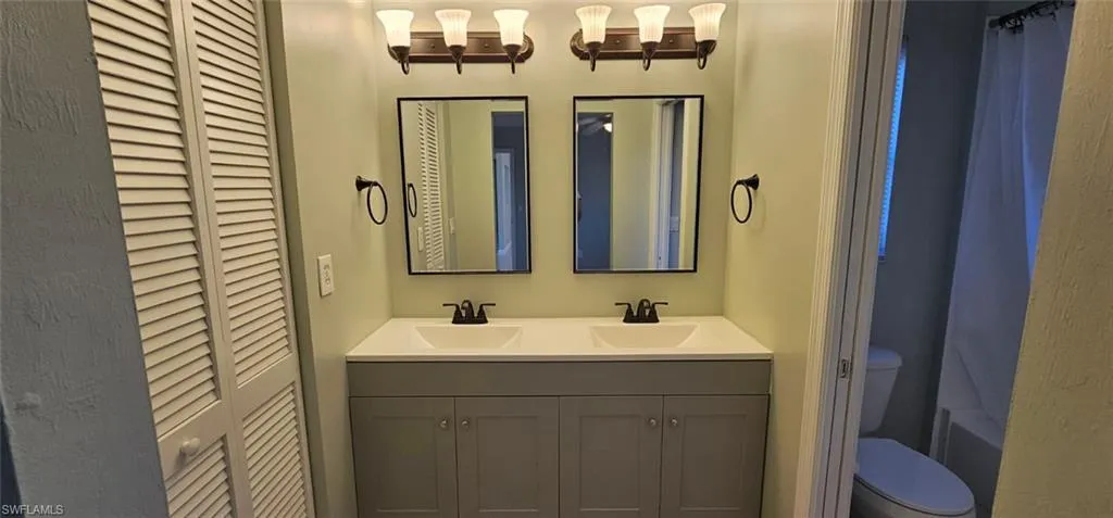Bathroom with a closet, double vanity, and shower / bathtub combination with curtain