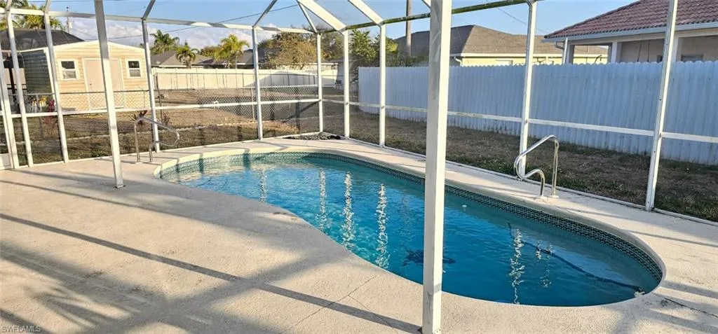 View of pool with a fenced backyard, a sunroom, glass enclosure, and patio surround