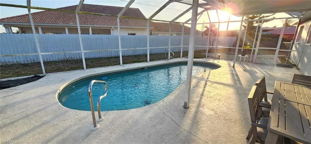 View of pool with glass enclosure, a fenced backyard, and patio surround