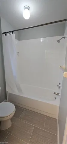 Full bath with shower / bathtub combination with curtain and toilet