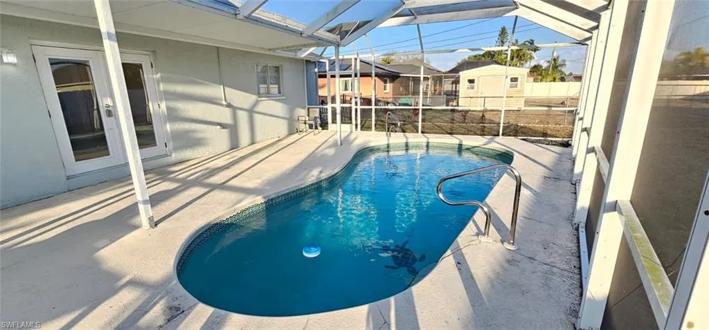 View of swimming pool featuring patio surround, a sunroom, a lanai, a residential view, and french doors