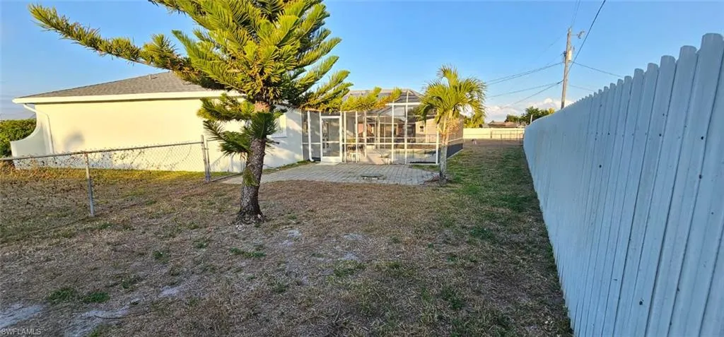 Fenced backyard with a sunroom, a patio, and a lanai