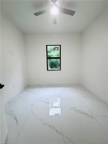 Empty room with light marble finish flooring and a ceiling fan