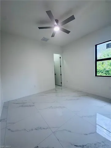 Unfurnished room featuring light marble finish flooring and a ceiling fan