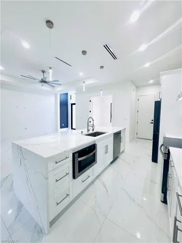Kitchen with light stone countertops, white cabinetry, a large island, stainless steel appliances, and pendant lighting