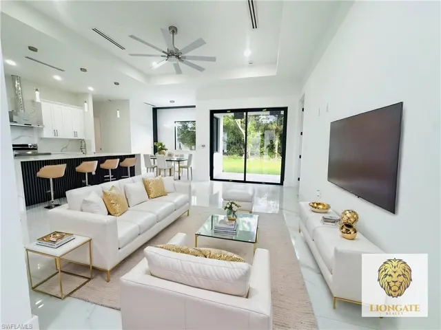 Living room with a ceiling fan, recessed lighting, and a raised ceiling. This room has been virtually staged