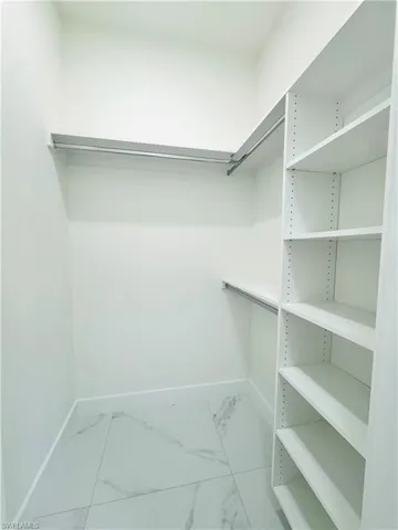 Walk in closet with light marble finish floors