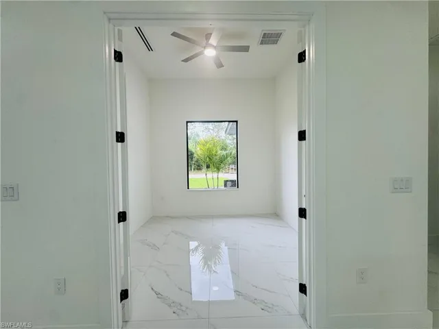 Empty room featuring a ceiling fan and light marble finish floors