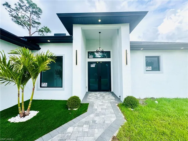 View of exterior entry featuring stucco siding and a lawn