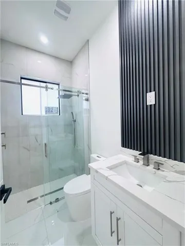 Bathroom featuring vanity and a marble finish shower