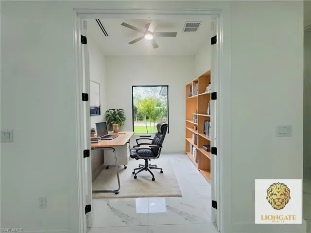 Home office featuring ceiling fan and light marble finish floors. This room has been virtually staged