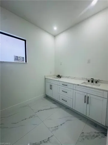 Bathroom with double vanity, light marble finish flooring, and recessed lighting. More upgrades to come on this bathroom.