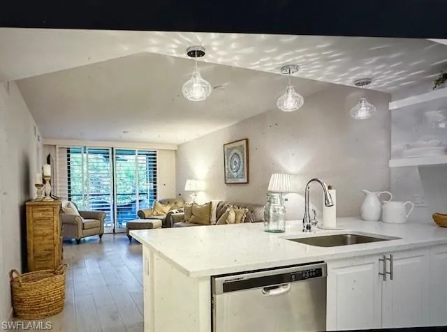 Kitchen with dishwasher, pendant lighting, light stone counters, white cabinetry, and a peninsula