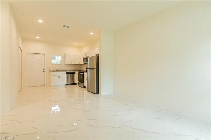Kitchen featuring light tile patterned flooring, stainless steel appliances, and white cabinets