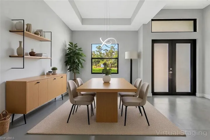 Virtual staged - Dining space featuring concrete floors, a tray ceiling, and french doors