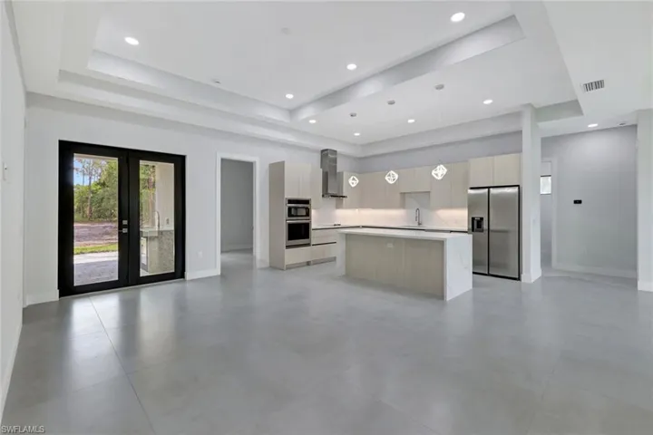 Kitchen featuring stainless steel appliances, modern cabinets, open floor plan, a kitchen island, and decorative light fixtures